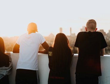 Four young people looking at a city view with their backs to the camera.