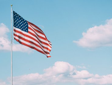 Amercian flag on blue sky and clouds background