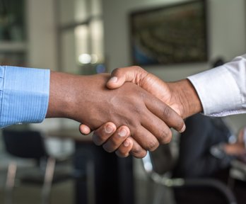 Two people shaking hands with only the hamds in view. 