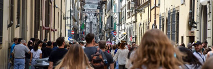 Tourists walking down a busy city street in Florence, Italy, on a summer's day. 