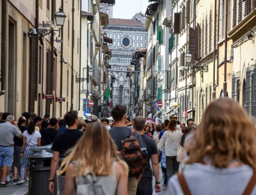 Tourists walking down a busy city street in Florence, Italy, on a summer's day. 