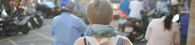 Person wearing backpack walking on road in busy city.