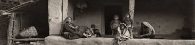 Black and white photograph of a group of Indigenous people sitting in front of a typical Limbu House in Eastern Nepal.