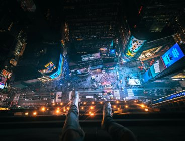 Person at the top of a building looking down onto a busy road at night
