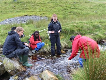 Group of pupils undertaking river fieldwork in a small stream.