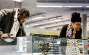 Two people looking at artefacts in a display cabinet in the Foyle Reading Room at the Society.