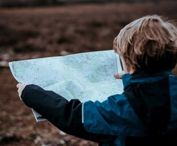 A young boy in the outdoors holding a map