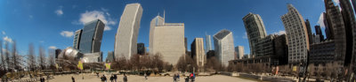 A huge silver coffee bean shaped structure in Chicago, which reflects the city skyline and blue skies