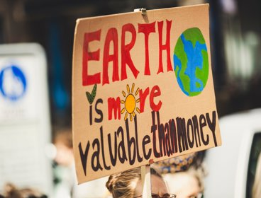 A sign that says 'Earth is more valuable than money'
