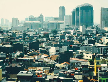 Skyline view of urban area in Jakarta, showing low buildings against a backdrop of highrise buildings.