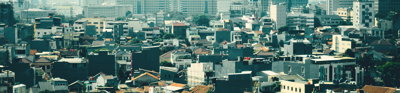 Skyline view of urban area in Jakarta, showing low buildings against a backdrop of highrise buildings.