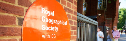 Sign on the outside of the Society's building close to the entrance, with three people walking in.