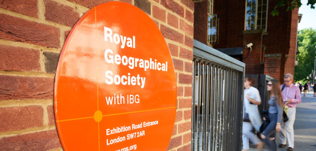 Sign on the outside of the Society's building close to the entrance, with three people walking in.