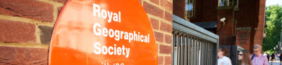 Sign on the outside of the Society's building close to the entrance, with three people walking in.