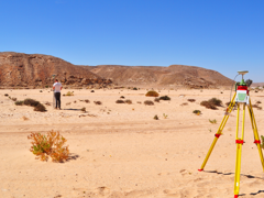 Researcher undertaking a topographic survey of an arid landscape using differential GPS equipment