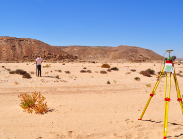 Researcher undertaking a topographic survey of an arid landscape using differential GPS equipment