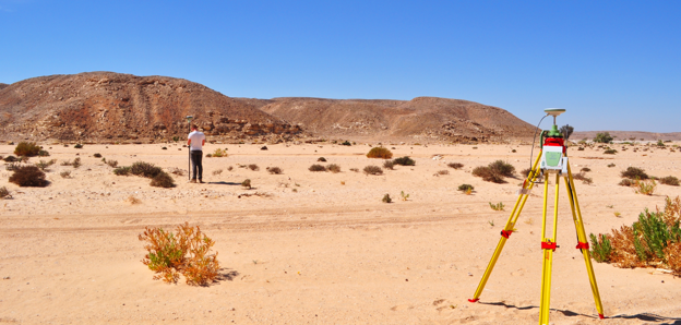 Researcher undertaking a topographic survey of an arid landscape using differential GPS equipment