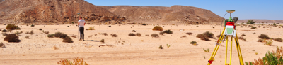 Researcher undertaking a topographic survey of an arid landscape using differential GPS equipment