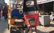 A rickshaw with the front end of a motorbike attached to the front