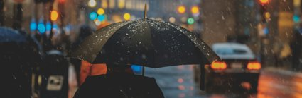 A person walking downa street holding an umbrella in the rain