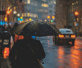 A person walking downa street holding an umbrella in the rain