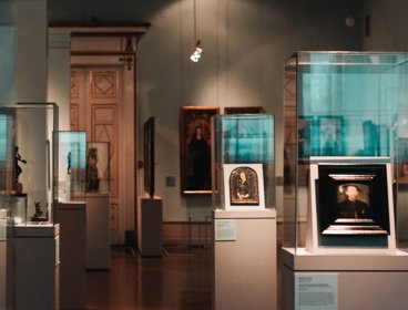 Sculptures and paintings displayed in glass cabinets in a museum exhibition
