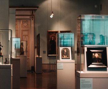 Sculptures and paintings displayed in glass cabinets in a museum exhibition