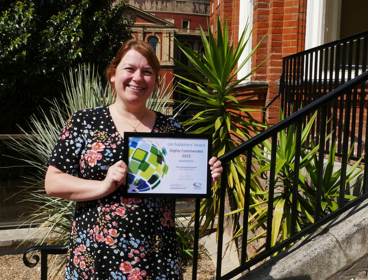 Rachel Owen holding the Geographical Association Publisher award for her resources, on the steps of the Society
