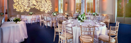 Round dinner tables setup in the Education Centre with a floral light projection on the wall.