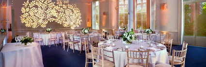 Round dinner tables setup in the Education Centre with a floral light projection on the wall.