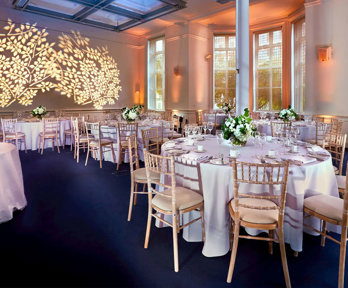 Round dinner tables setup in the Education Centre with a floral light projection on the wall.