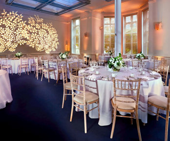 Round dinner tables setup in the Education Centre with a floral light projection on the wall.