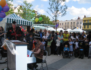 Person playing a piano to a crowd on the street