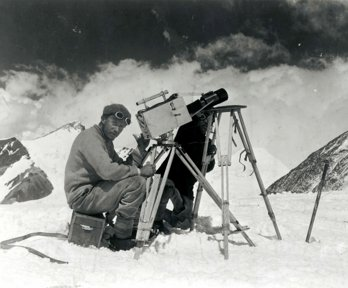 Historic black and white photograph of two men taking photographs in a snowy mountainous environment