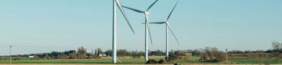 A row of wind turbines in a field against a backdrop of a blue sky.