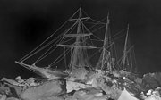 Old black and white photo of the Endurance stuck in ice at night.