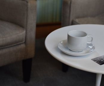 A coffee table with a cup and saucer and a card that says Royal Geographical Society.