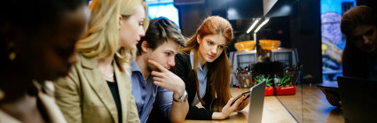 A group of people crowded around a laptop looking at the screen.