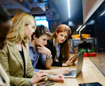 A group of people crowded around a laptop looking at the screen.