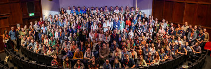 Group photo of RGS Explore 2024 attendees on the stage of the Ondaatje Theatre