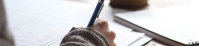 Close up of a person writing at a desk. 