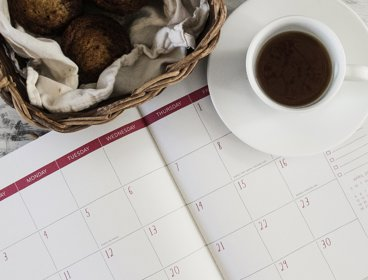 Calendar open on desk with a cup of coffee next to it