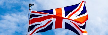 A union jack flag flying in the wind on a blue sky background