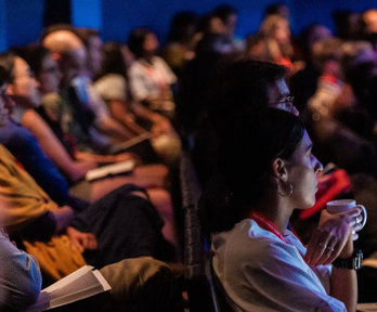 People sat in a theatre with laptops.