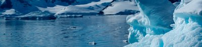 A large, floating iceberg surrounded by snow-covered mountains.