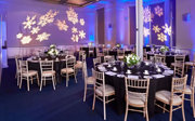 Round dinner tables setup in the Education Centre with a snowflake light projection on the wall.