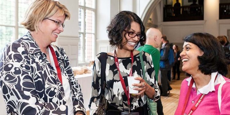 Three people chatting while attending an informal drinks reception in the Main Hall at the Society.