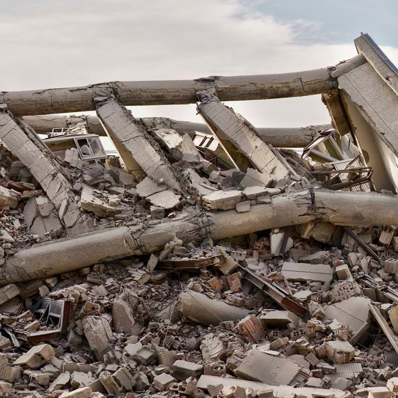 A pile of grey-brown rubble that was once a building, having been destroyed by an earthquake