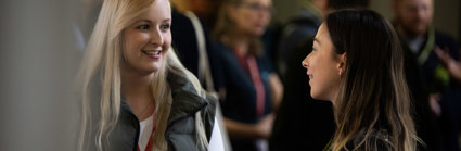 Two people at a conference smiling whilst engaged in a lively conversation.