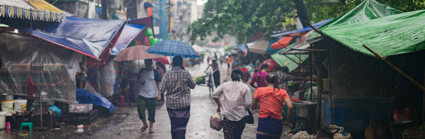 People walk through an informal market settlment whist its rains